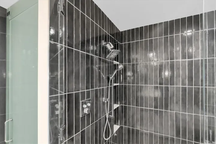 Frameless glass shower with rain fixture and dual shower heads.
