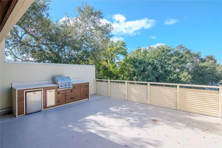featuring an outdoor kitchen with grill and fridge