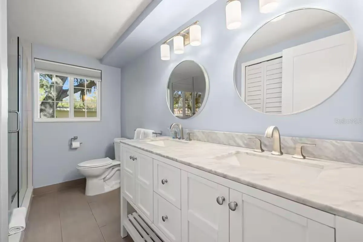 Updated full bath features a DOUBLE-SINK VANITY, modern lighting, generous counter space, and a walk-in shower.