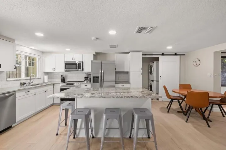 Another view highlights the generous island, open dining area, and convenient tucked-away laundry—all seamlessly connected to the main living spaces.