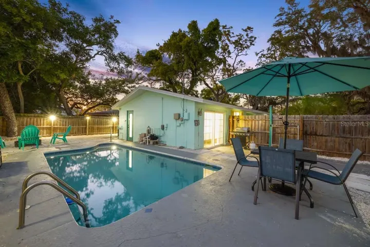 Evening lighting shows off the backyard’s resort-like setup, complete with heated pool, outdoor dining, BBQ area, and space to gather around the fire pit.