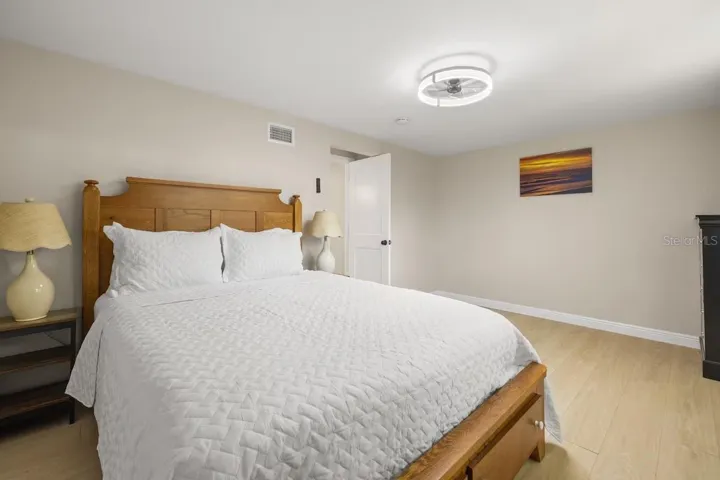 Spacious third bedroom with LVP flooring, modern ceiling fan, and flexible space for guests, a home office, or both.