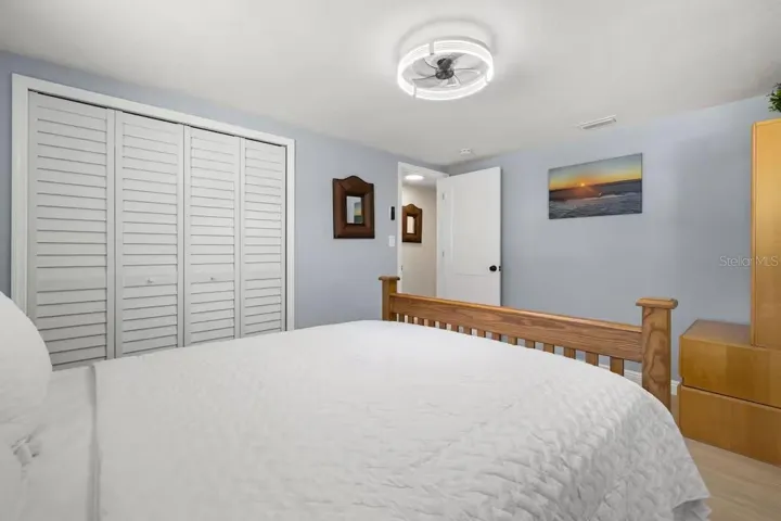 Comfortable guest bedroom with LVP flooring, ceiling fan, and a full wall of closet space for plenty of storage.