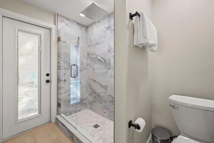 Beautifully updated ensuite features an oversized walk-in shower with floor-to-ceiling tile, frameless glass enclosure, and rainfall showerhead.