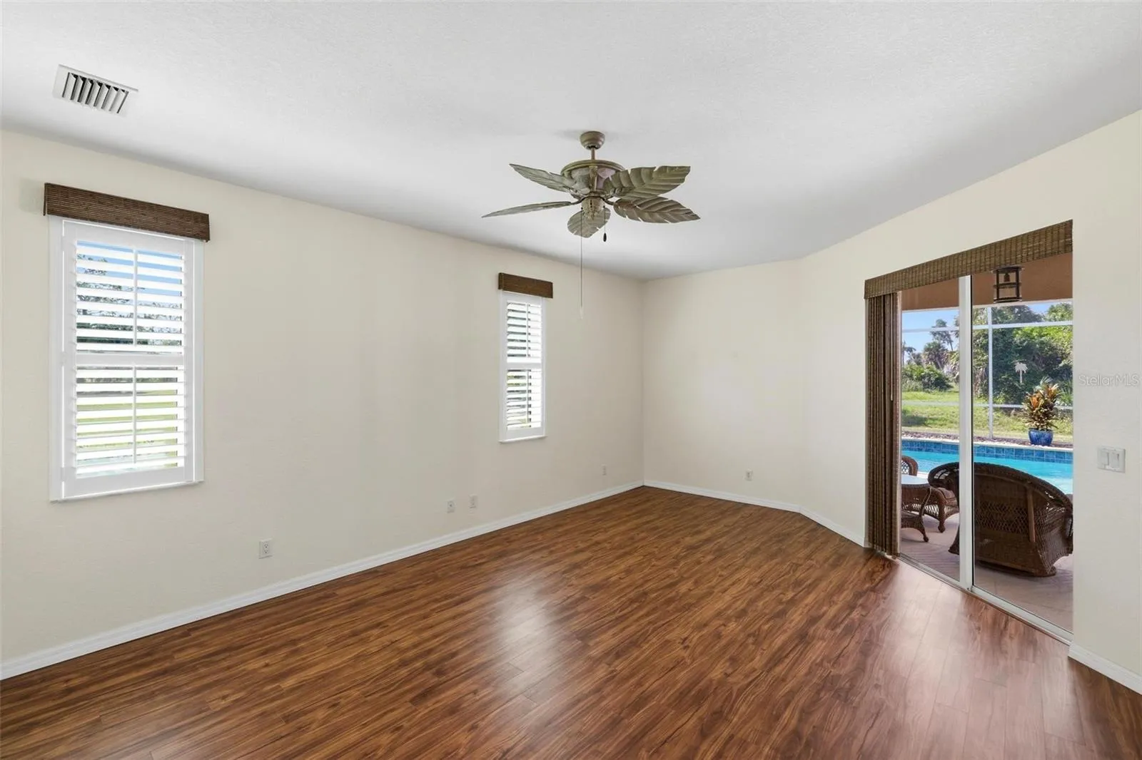 Primary Bedroom with vinyl plank flooring.... pocket sliding glass door out to the lanai/pool