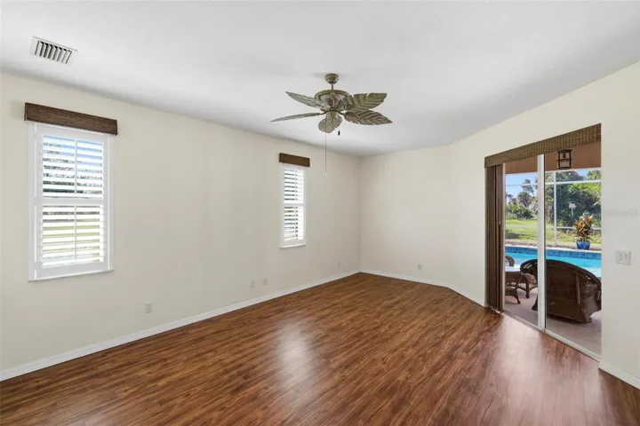 Primary Bedroom with vinyl plank flooring.... pocket sliding glass door out to the lanai/pool