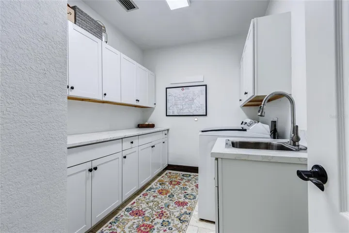 Cabinets galore in laundry room and utility sink!