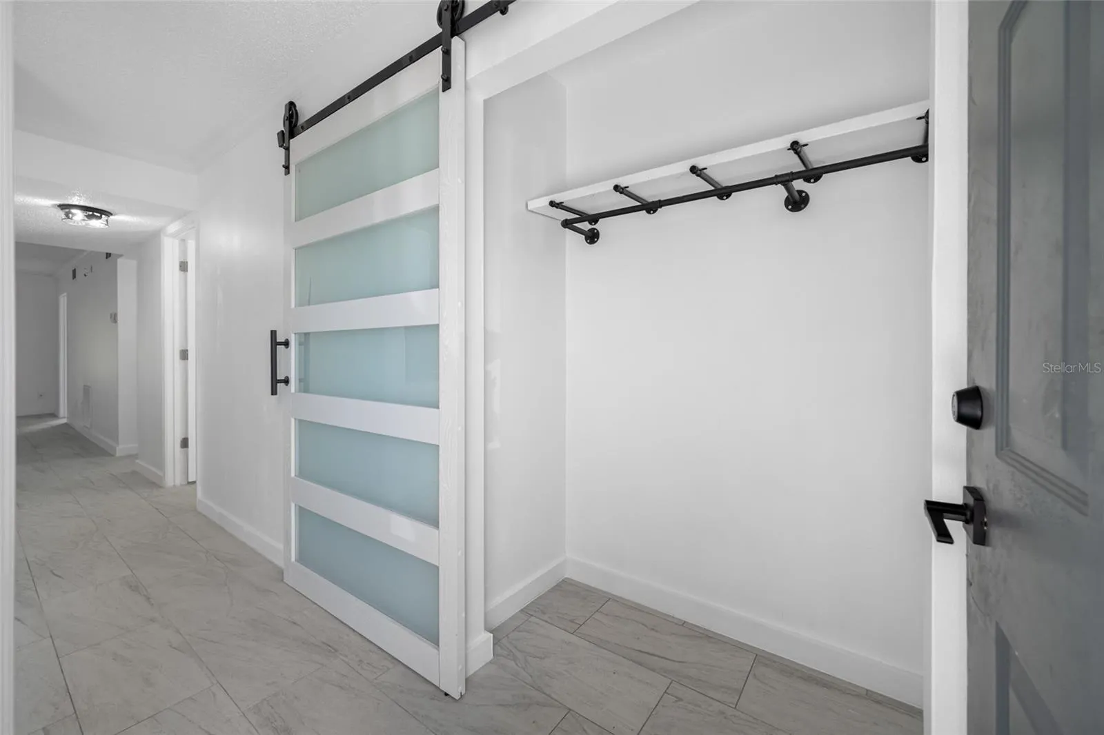 Entry closet with modern frosted-glass barn door.