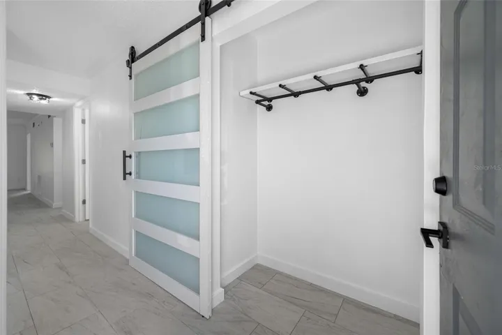 Entry closet with modern frosted-glass barn door.