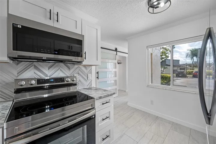 Stainless steel range and microwave with a Carrara marble chevron-patterned backsplash.