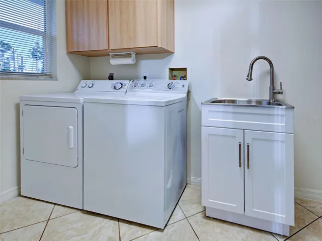 The laundry room is spacious and has a sink and faucet.