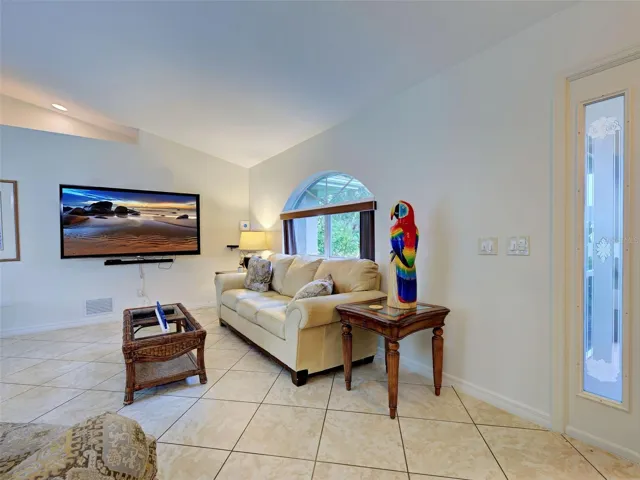 The spacious living room has vaulted ceilings and diagonally laid tile.