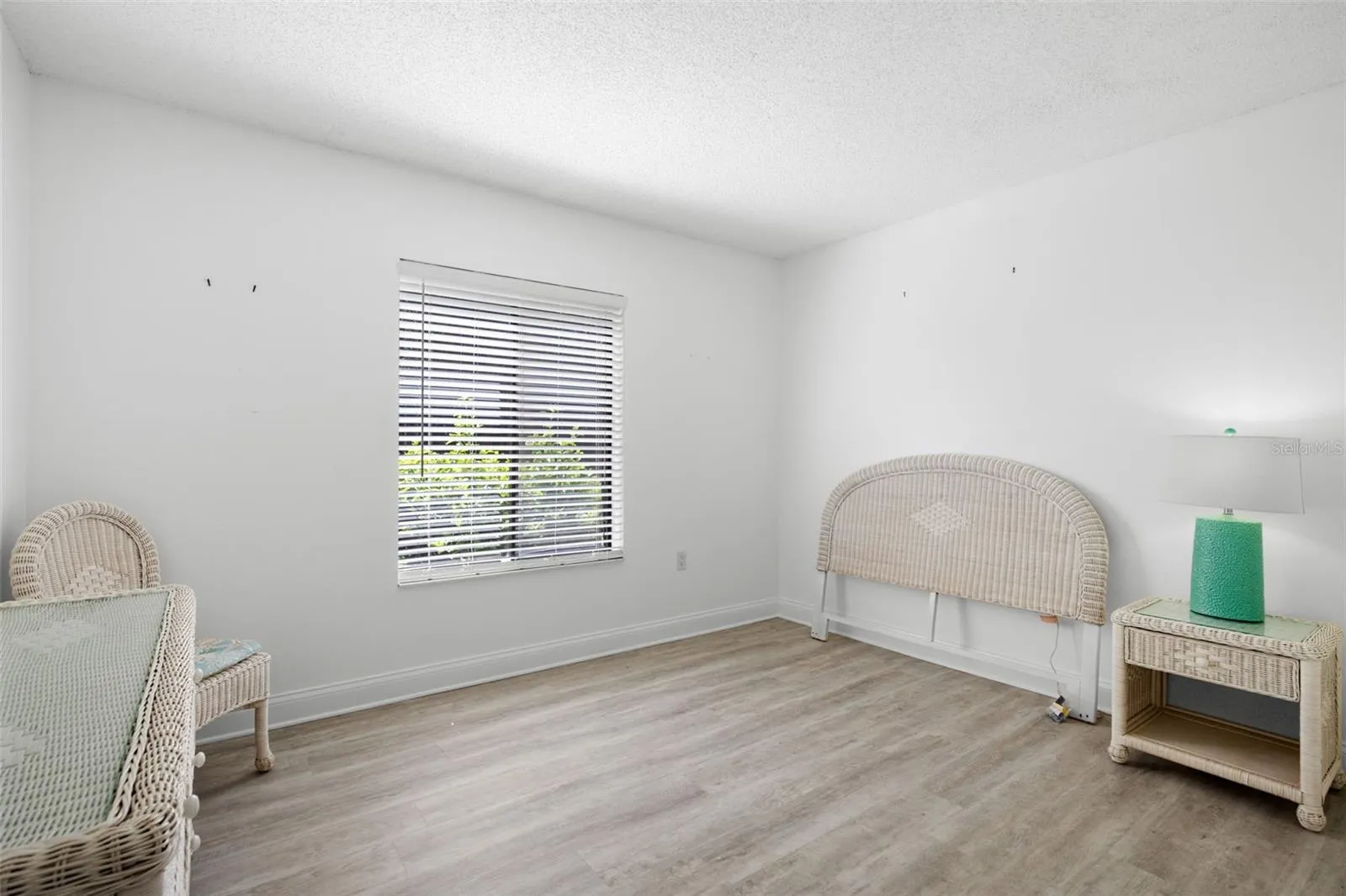 The second bedroom is bright and versatile, with light-toned flooring, a large window, and enough space to serve comfortably as a guest room, home office, or both.