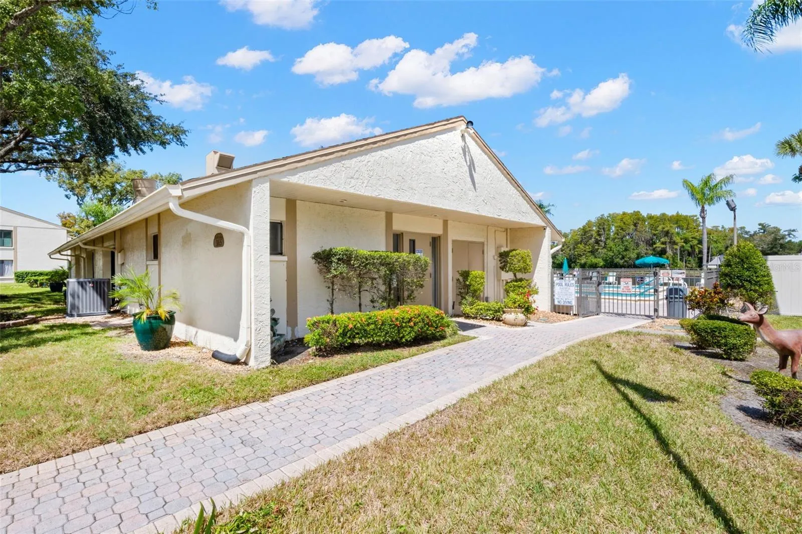 The clubhouse sits just steps from the pool, surrounded by landscaped grounds and paved walkways that make the community amenities easy to enjoy.