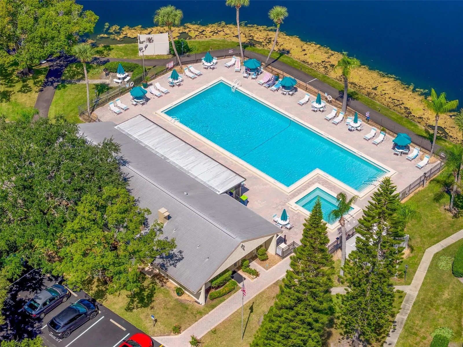 A pristine lakeside pool anchors the community’s recreation area, surrounded by palm trees, lounge seating, and a separate spa—an inviting place to swim, unwind, and enjoy the Florida sunshine.