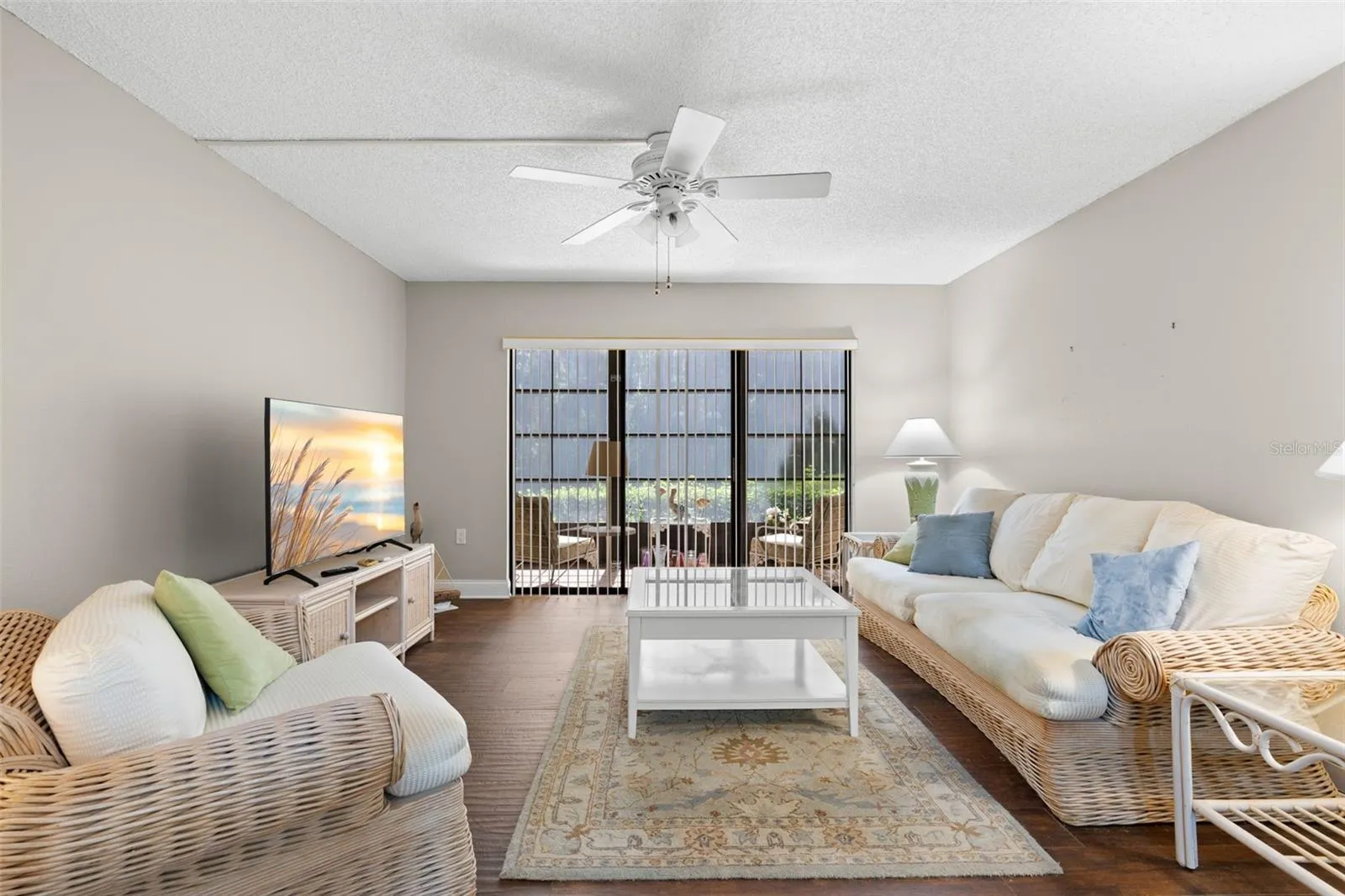 The living room is comfortably proportioned, with a wide bank of sliders extending the view toward the screened lanai and creating an easy indoor-outdoor connection.