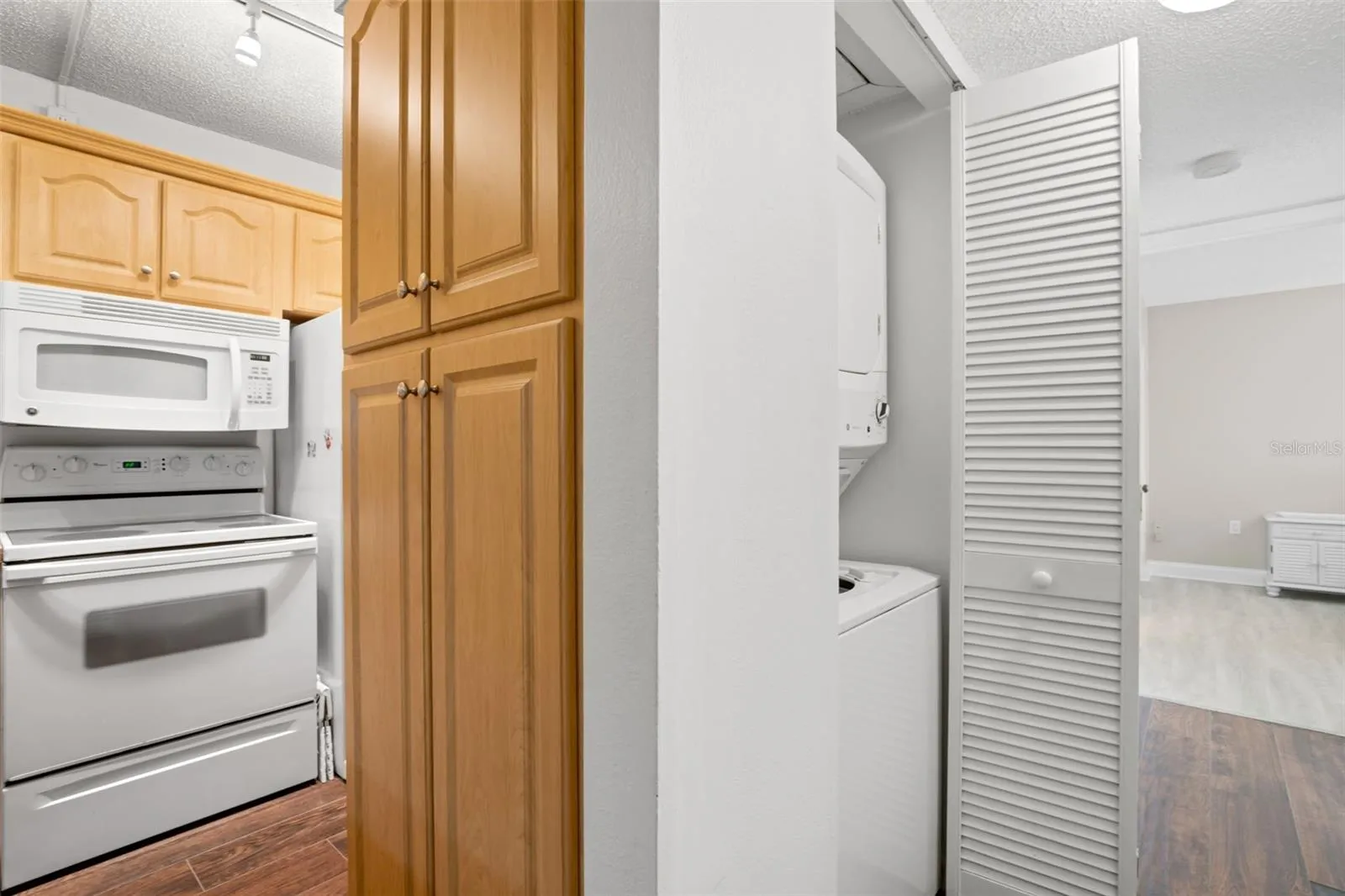 A dedicated laundry closet just off the kitchen keeps the stacked washer and dryer neatly tucked away, with additional built-in cabinetry close at hand.