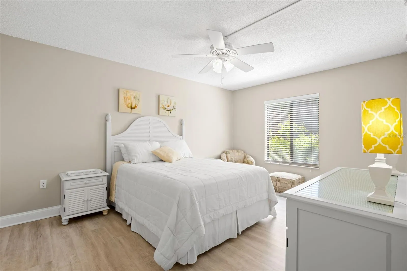 The primary bedroom continues the home’s neutral color palette, with a ceiling fan, soft natural light, and plenty of room for a full bedroom suite.