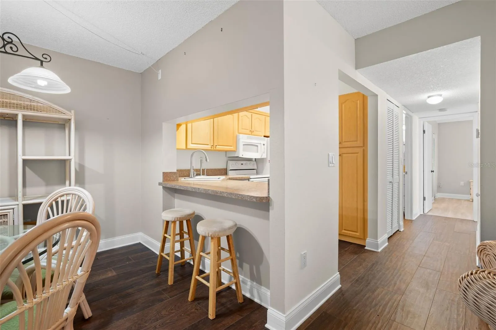 From the dining area, the breakfast bar provides casual seating while the adjoining hallway leads to both bedrooms, baths, and the in-unit laundry.