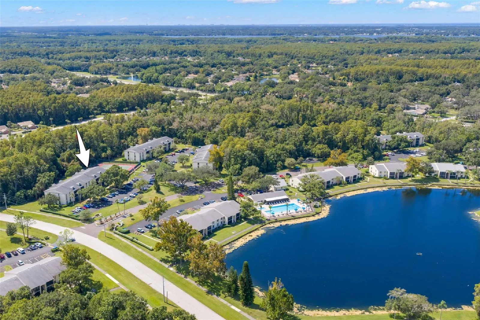 The arrow shows Building 218 within the community, with the pool, clubhouse, lake, and surrounding green space all close by.