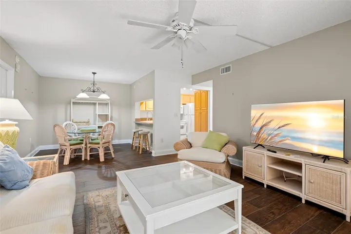 Neutral tones, a ceiling fan, and 2021 wood-look tile flooring carry through the open living and dining areas, with a pass-through connecting the kitchen to the main living space.