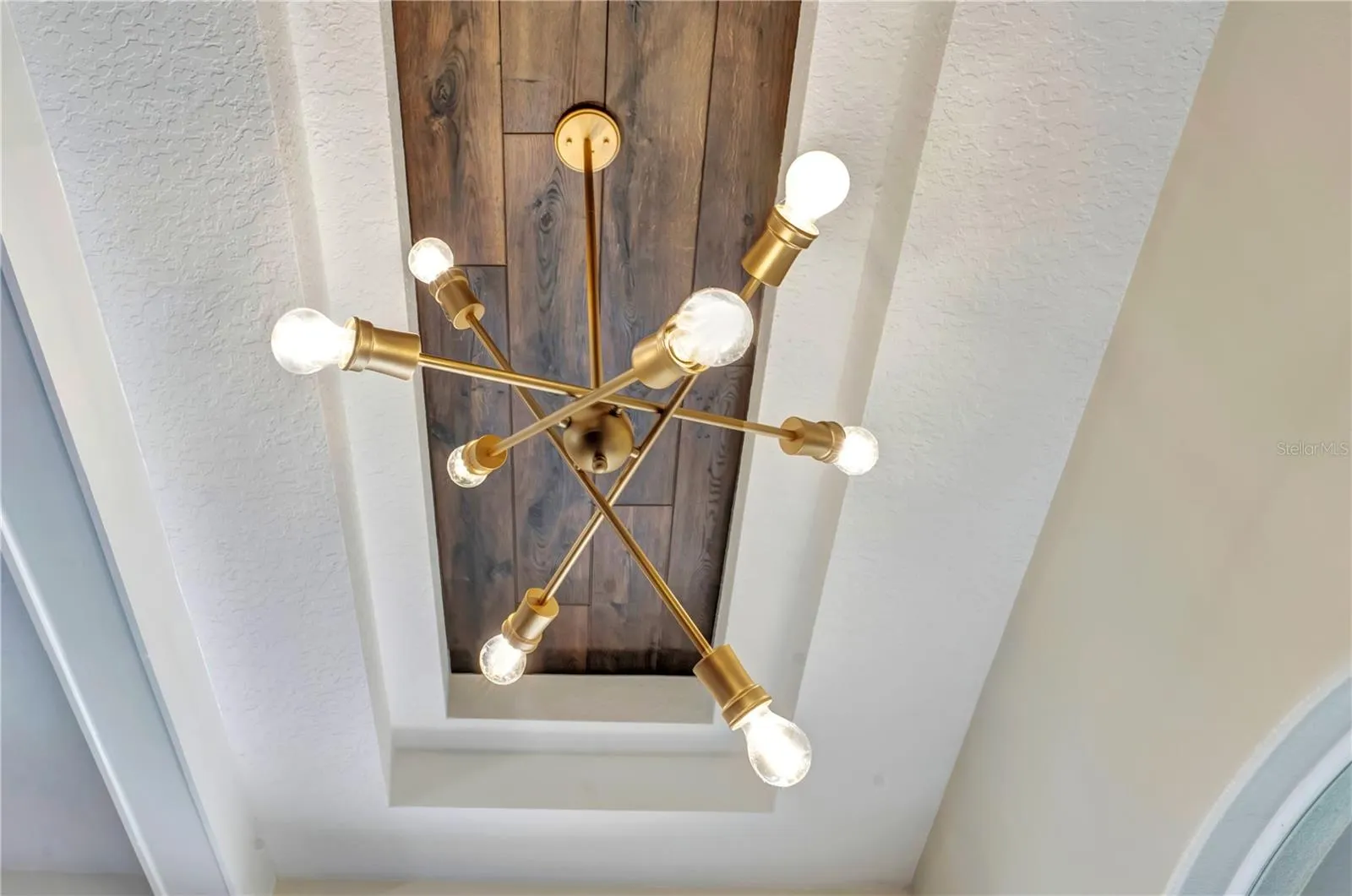 Brass sputnik chandelier in a wood-plank tray ceiling.