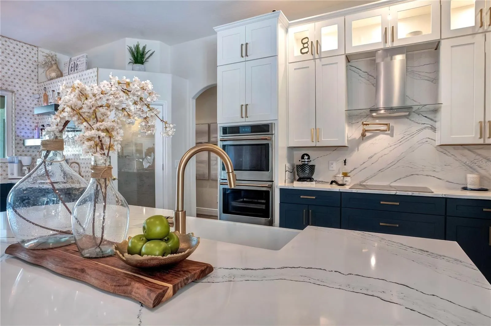 Pot filler, Cambria slab backsplash and gold fixtures.