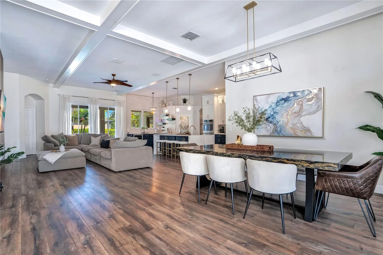 Dining, living and kitchen flow under a coffered ceiling.