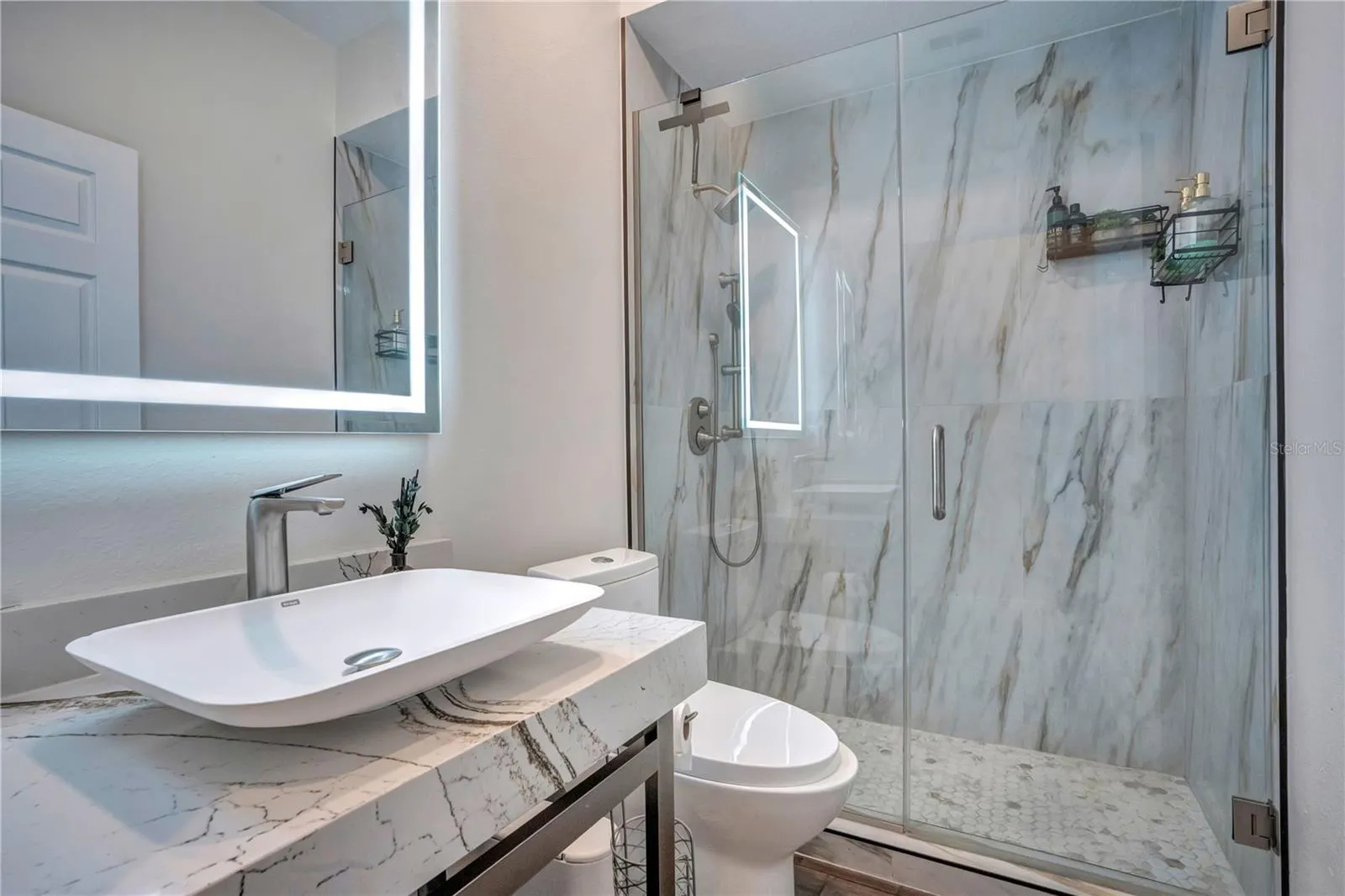 Cambria shower walls, frameless glass and lit mirror.