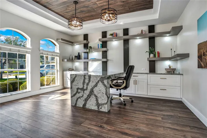 Office with Cambria waterfall desk, lit floating shelves and built-ins.