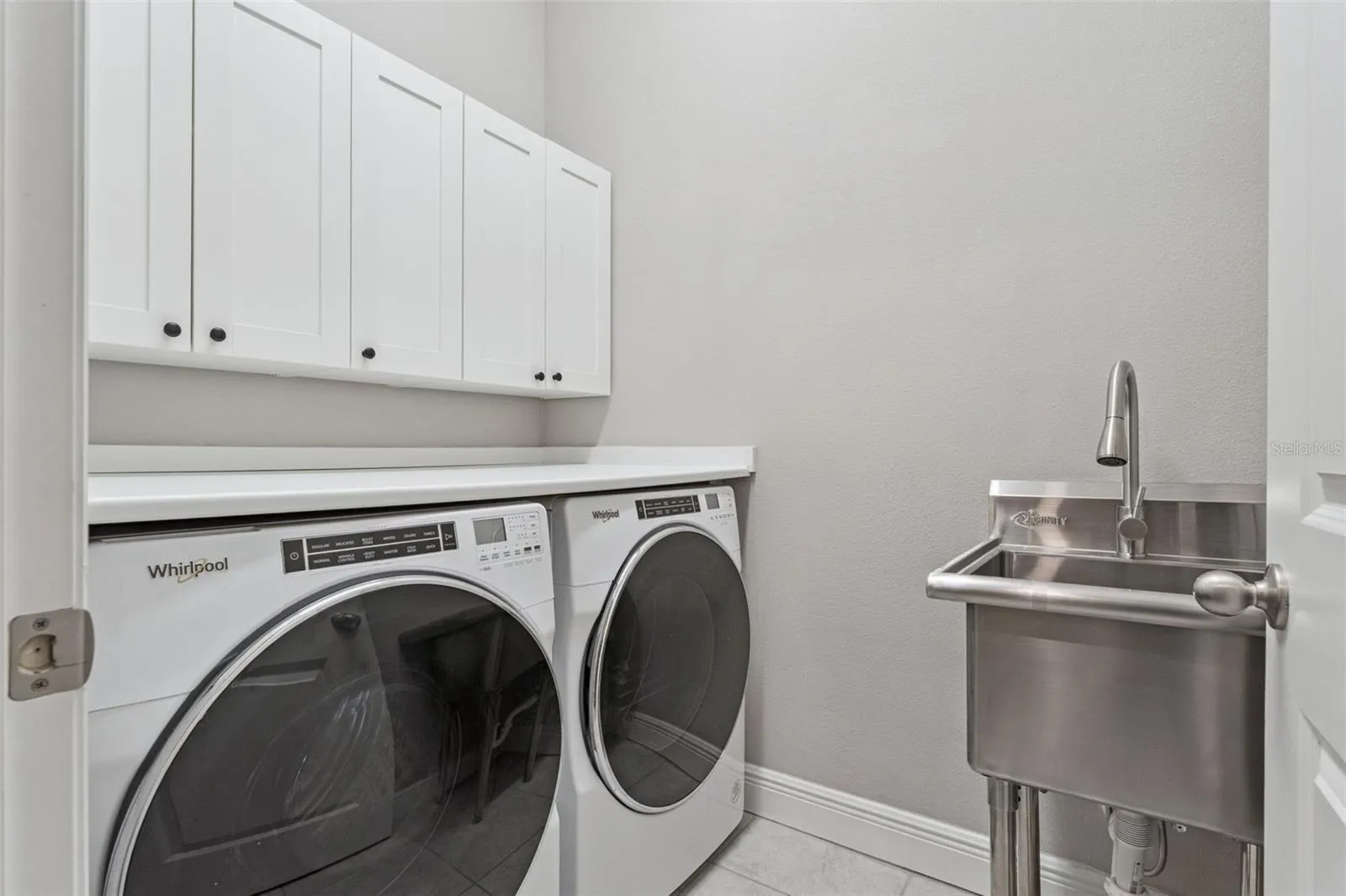 Convenient laundry room with upper cabinetry and space for full-size appliances.