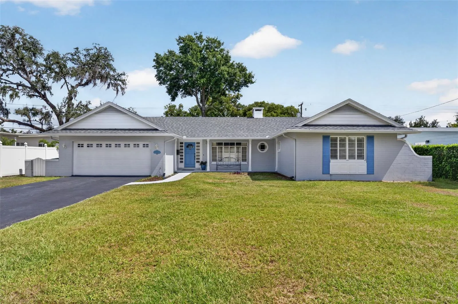 Front Exterior — Block-constructed, single-story home with an attached two-car garage, large-format windows and a welcoming covered front porch.