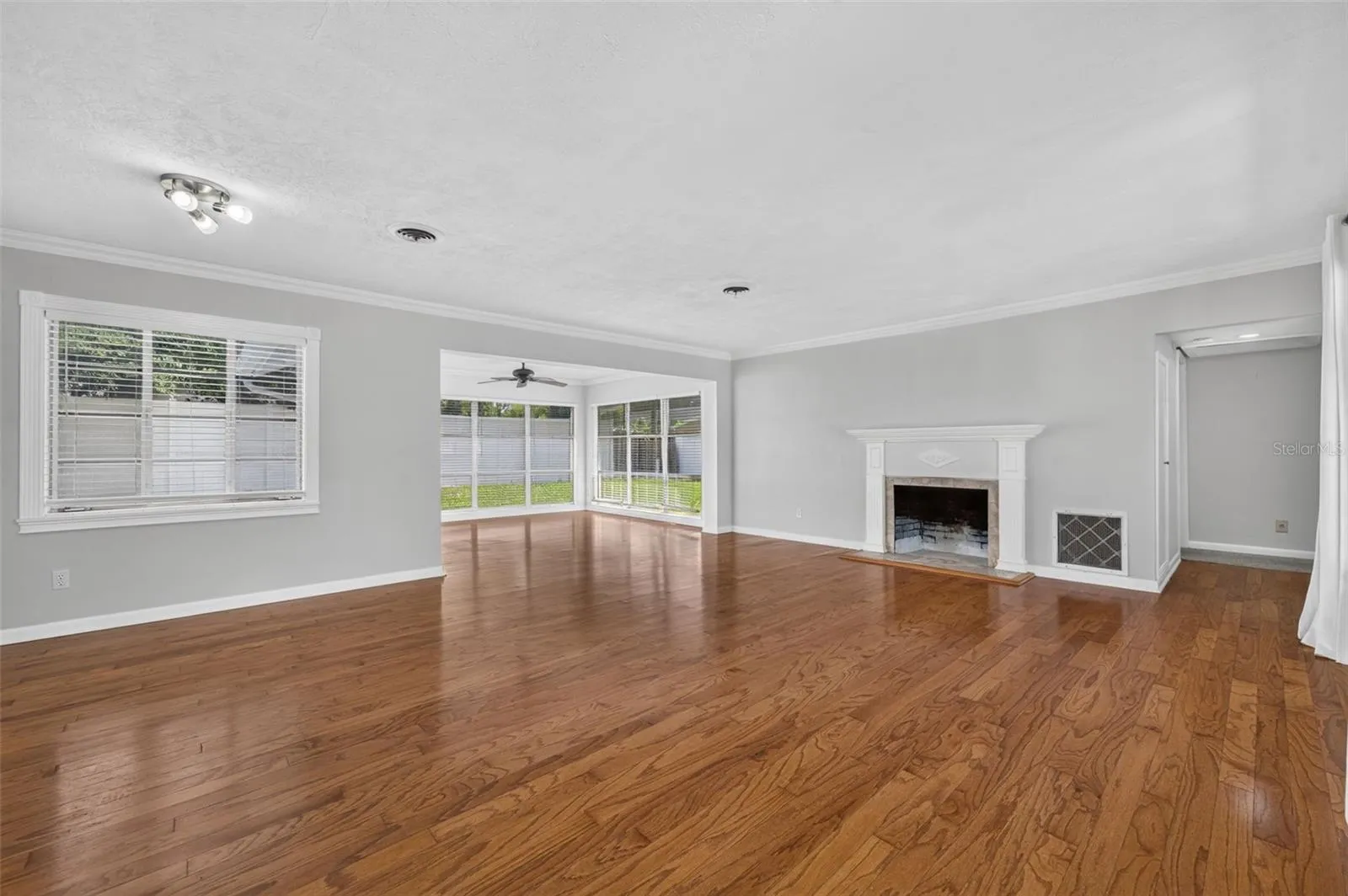 Living &amp; Dining Area — Spacious combined living and dining area with hardwood floors, crown molding, fireplace, detailed millwork and abundant natural light from large-format windows.