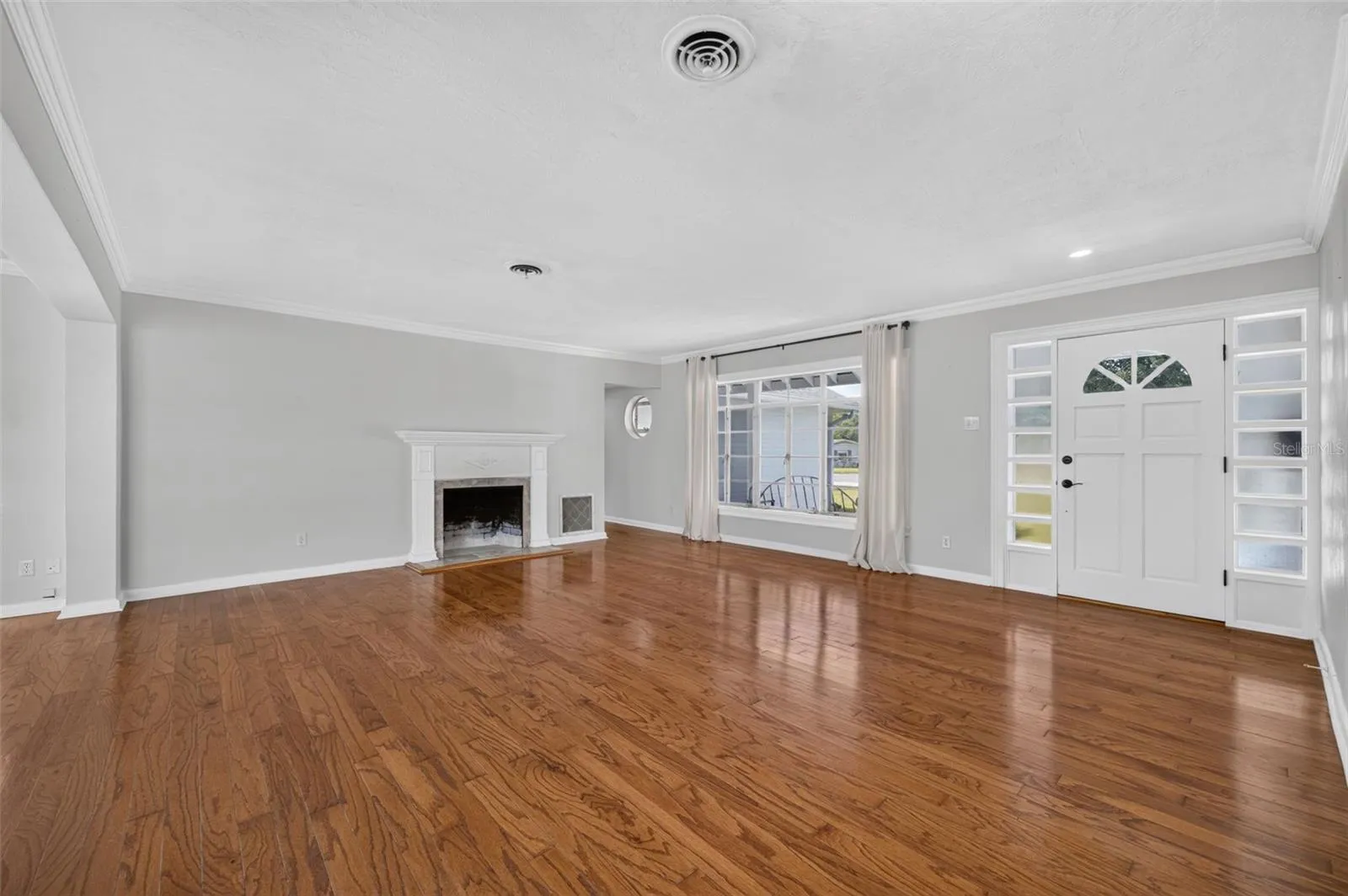 Living Area — Another view of the main living space highlighting the hardwood floors, fireplace, crown molding and natural light.