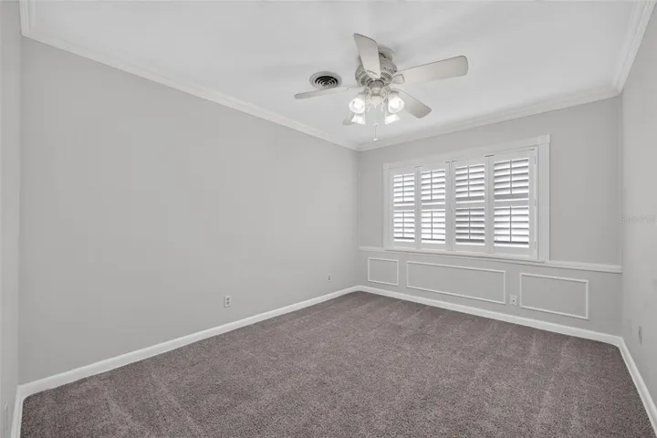 Alternate Bedroom — Ample-sized alternate bedroom with neutral carpeting, crown molding and custom interior shutters.