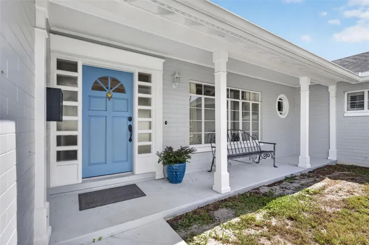 Covered Front Porch — Welcoming covered porch with a distinctive blue front door framed by detailed millwork and sidelights.
