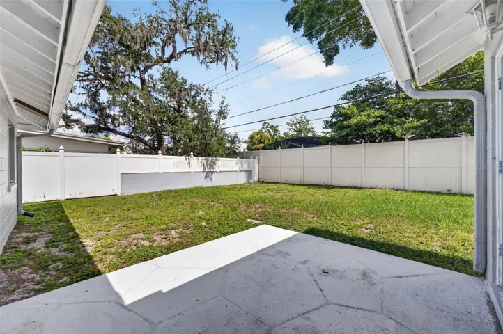 Covered Patio &amp; Backyard — Covered rear patio opens to the spacious, almost fully fenced backyard.
