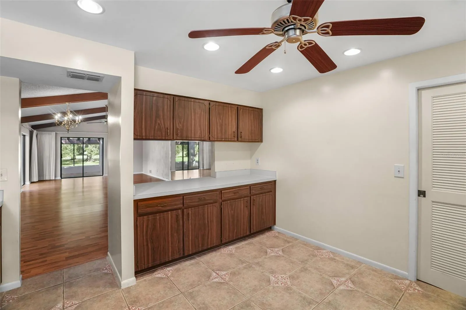 The kitchen’s generous footprint leaves room for a casual breakfast table or additional storage along the open wall. Recessed lighting, a ceiling fan, abundant cabinetry, and a wide pass-through to the living and dining area keep the space practical and connected.