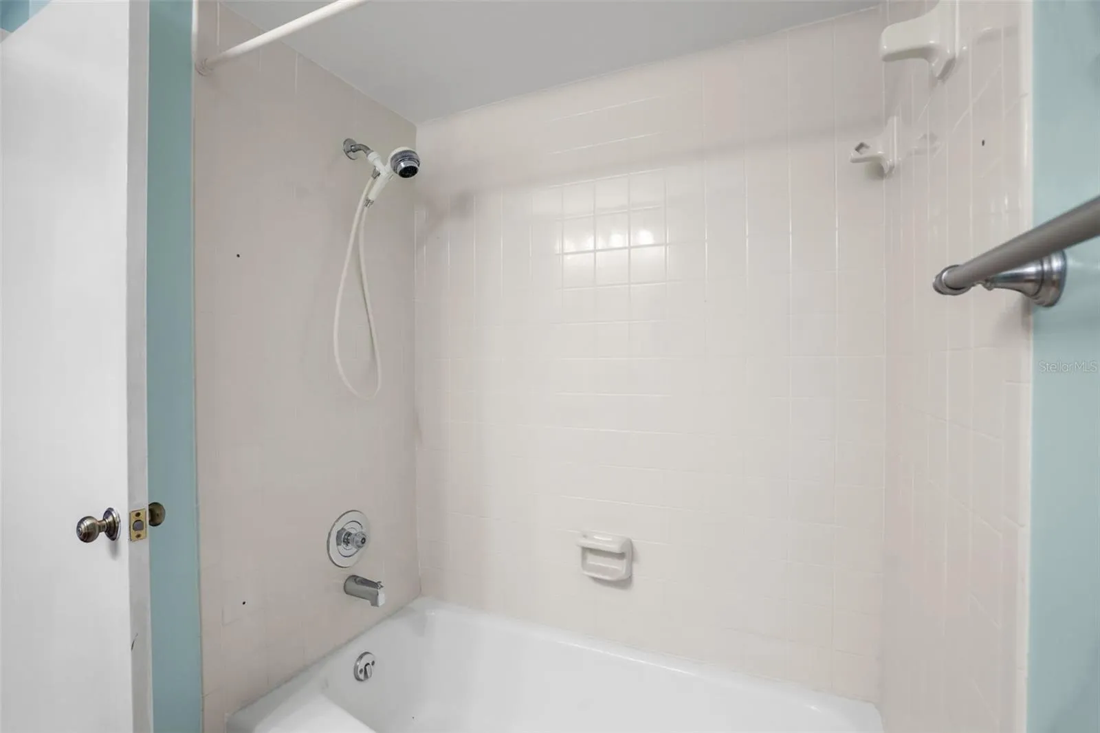 The second bath’s tub-and-shower combination is finished with light tile and includes a handheld showerhead and built-in soap dishes. It keeps the room practical for everyday use, guests, or anyone who prefers a tub over a walk-in shower.