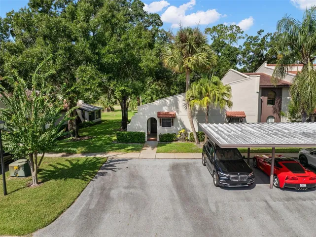 A coveted end-unit location adds extra separation, side green space, and a more private feel, while dedicated covered parking sits just steps from the front door. Mature trees and palms soften the setting around this villa-style condo.