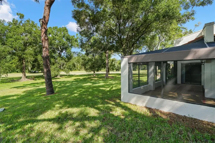 The wraparound screened lanai opens to a wide stretch of lawn shaded by mature trees, with the golf course just beyond. It’s an unusually open setting for a condo, giving the outdoor space a quiet, tucked-away feel without sacrificing the convenience of community living.