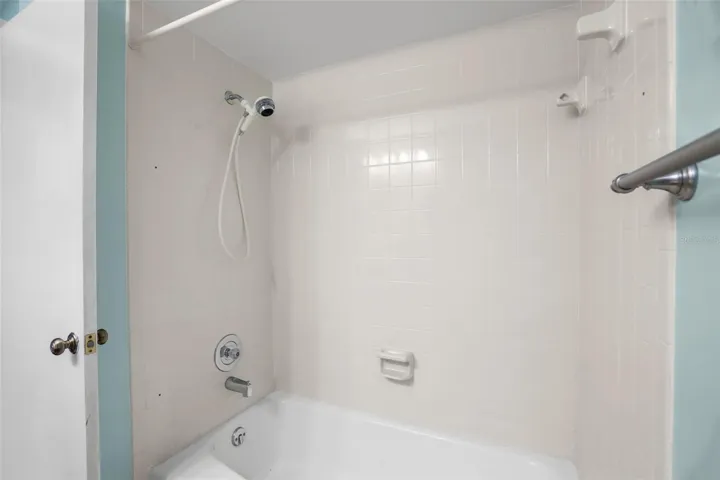 The second bath’s tub-and-shower combination is finished with light tile and includes a handheld showerhead and built-in soap dishes. It keeps the room practical for everyday use, guests, or anyone who prefers a tub over a walk-in shower.