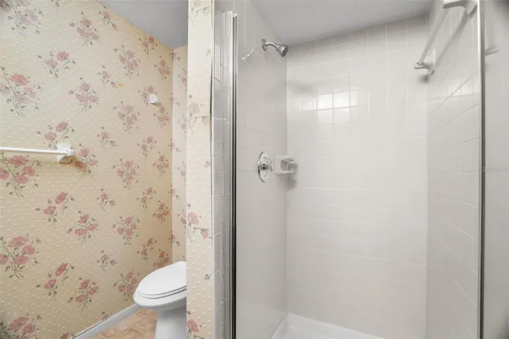 A separate tiled shower and private toilet area complete the primary bath, keeping the wet area distinct from the long double vanity. The layout offers a practical starting point for anyone who wants to modernize the finishes over time.