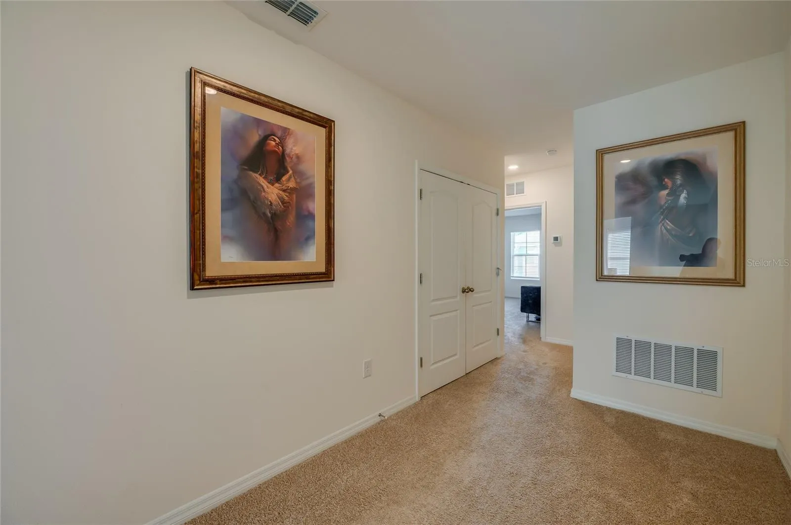 Open upstairs landing provides flexible circulation space with neutral carpeting, recessed lighting, and convenient closet storage.