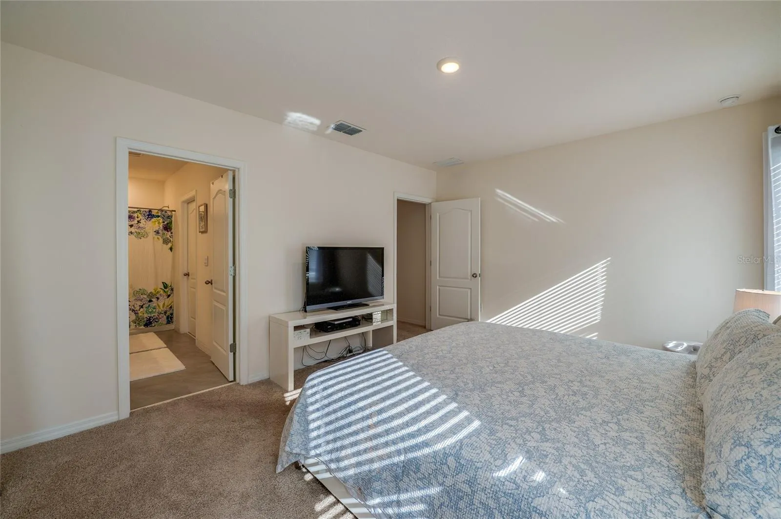 Additional view of the bedroom highlights its generous proportions and convenient direct access to the adjoining bathroom.