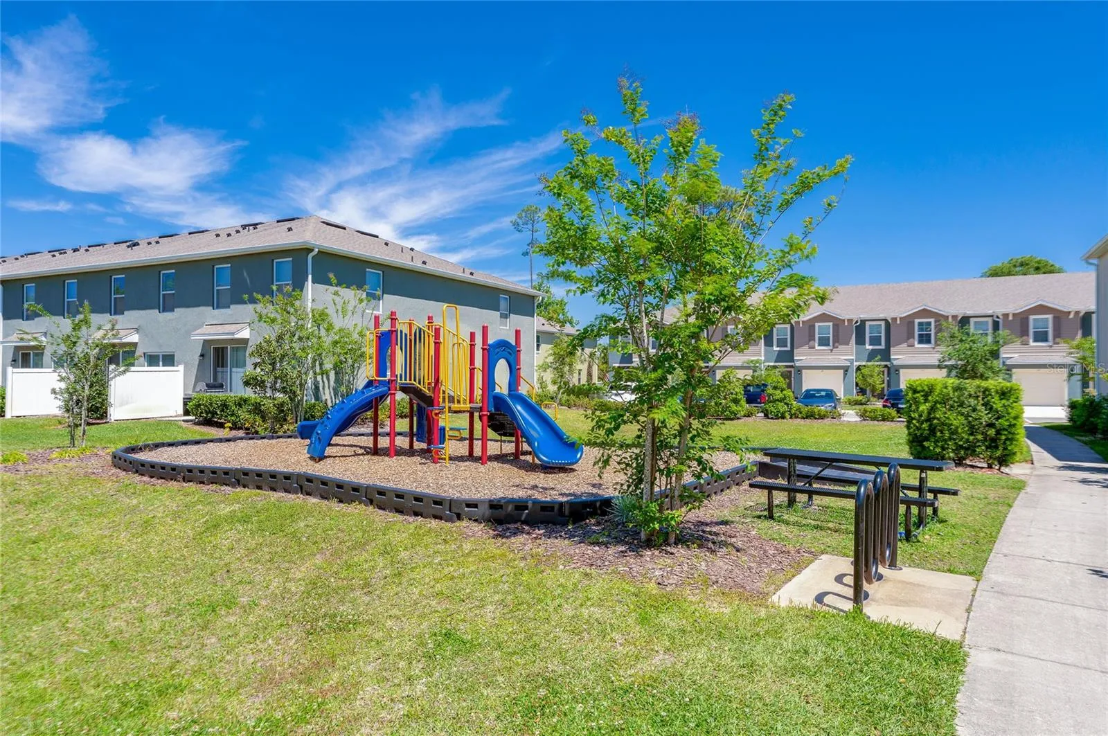 Neighborhood playground offers outdoor recreation space with play equipment, a picnic table, and surrounding lawn.