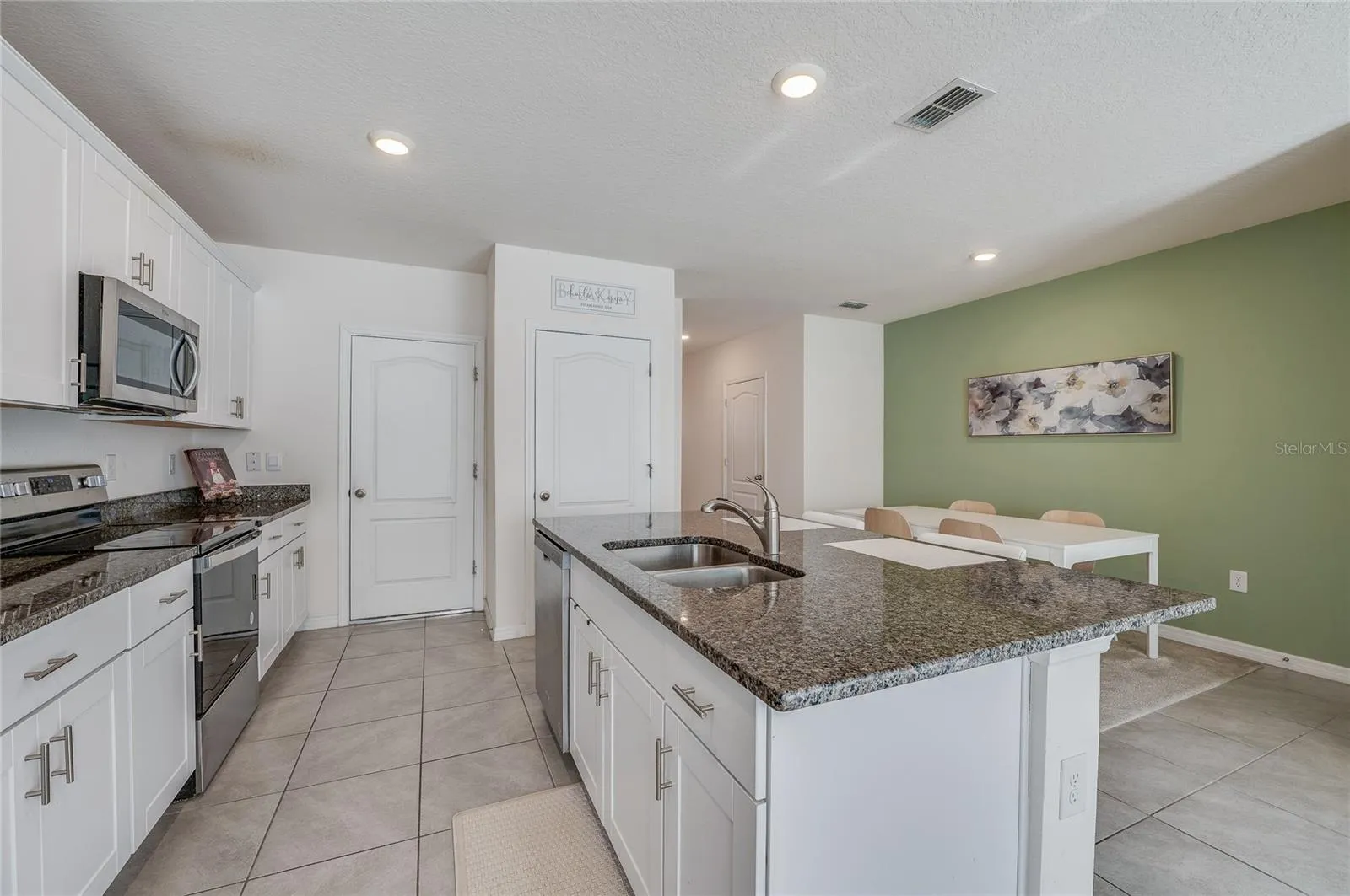 Another view highlights the kitchen’s large island with double-basin sink and the easy connection to the adjacent dining area.