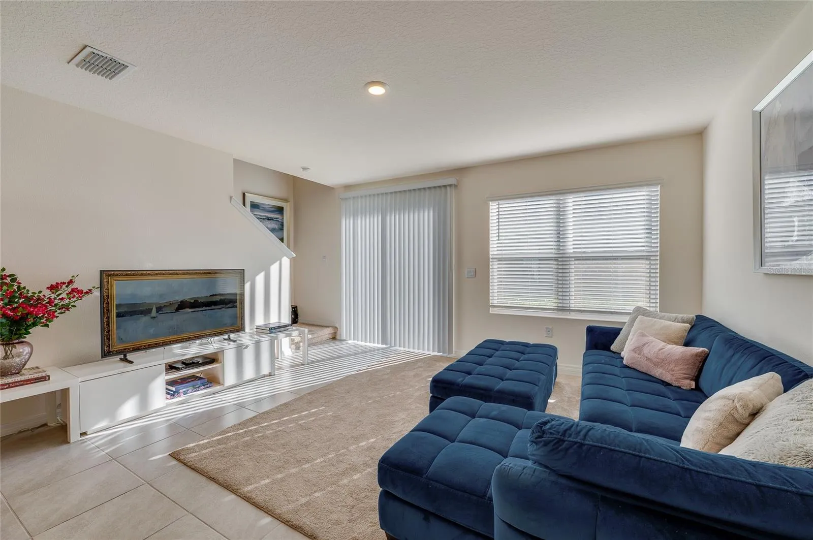 A second living-room perspective showcases the generous gathering space, abundant natural light, and convenient access toward the outdoor area.