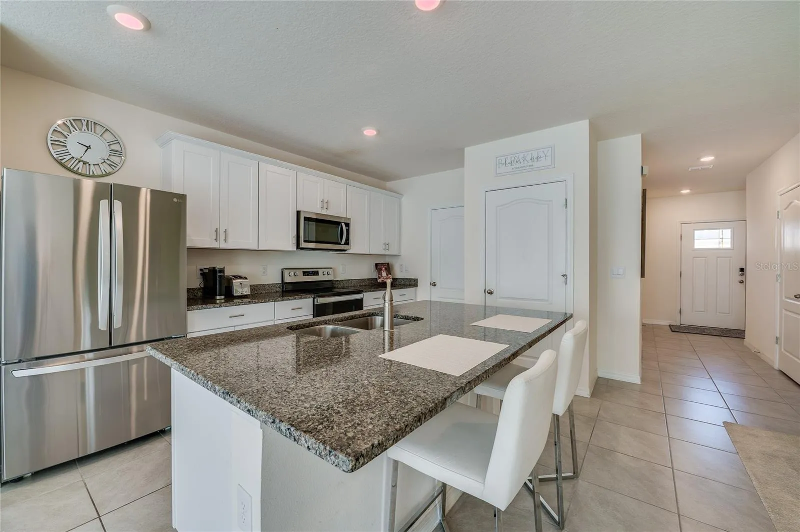 Spacious center island provides abundant prep and serving space, complemented by granite countertops, stainless steel appliances, and ample cabinetry.