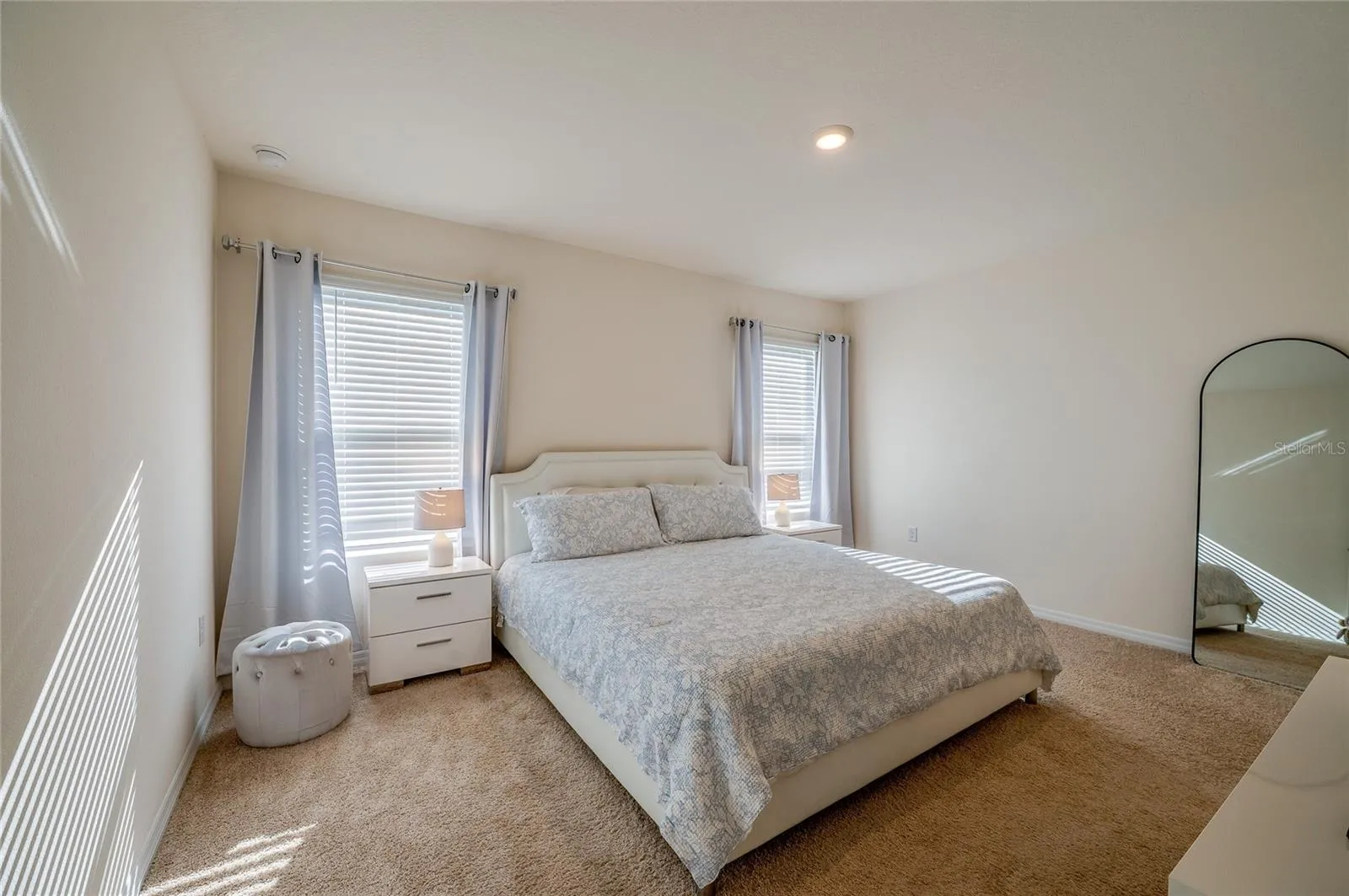Spacious bedroom features neutral carpeting, recessed lighting, and multiple windows that bring in abundant natural light.